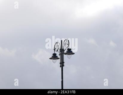 Pied de lampe en métal noir avec deux lampes, abat-jour noir et le fer circulaire cintre les globes de verre contre le ciel bleu Banque D'Images