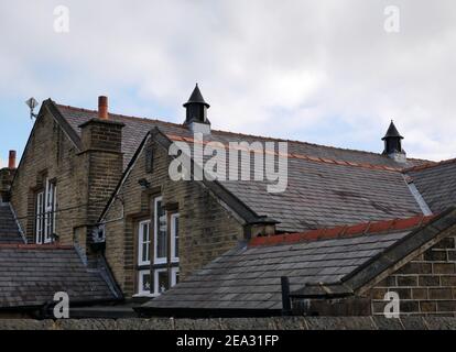 Bâtiment construit en pierre avec plusieurs toits d'ardoise en terre cuite coiffant les deux panneaux et cheminées de toit Banque D'Images