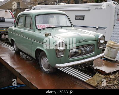 L'ancienne voiture verte à quatre portes du préfet se tenait sur des poutres métalliques avec caravane en arrière-plan Banque D'Images