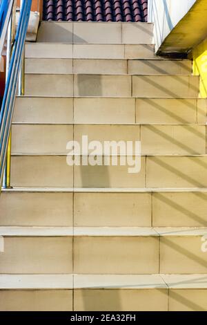 Vue rapprochée des escaliers avec carreaux jaunâtres et garde-corps Banque D'Images