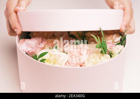 Gros plan les mains des femmes ouvrant les boîtes-cadeaux avec des fleurs fraîches. Le printemps arrive, journée internationale des femmes, bonne Saint Valentin, 8 mars, fête des mères Banque D'Images