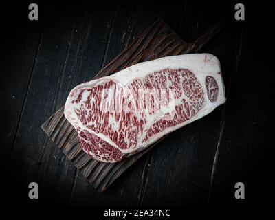 Morceau de bœuf Wagyu. Steak de bœuf cru sur fond de bois dans un boucher. Produit japonais haut de gamme.