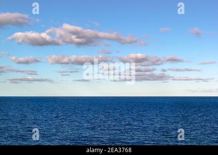 La mer Baltique bleue touchant l'horizon. Nuages blancs clairs entrant dans l'image depuis la gauche. Une scène tranquille et paisible. Cette image invite à penser Banque D'Images