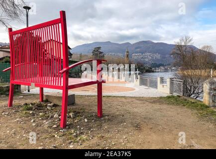 La promenade au bord du lac de Lavena Ponte Tresa avec le Maxi Bench rouge, province de Varèse, Italie Banque D'Images