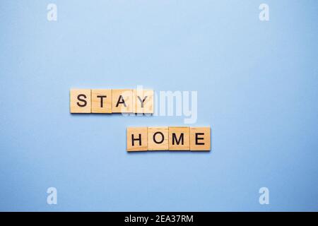 Lettres décoratives en bois formant le mot rester à la maison sur un fond blanc, vue de dessus Banque D'Images