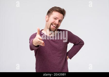 Homme d'âge moyen souriant amical offrant poignée de main comme salutation et accueillant. Prise de vue en studio Banque D'Images