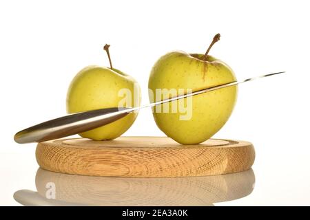 Un tout et un, incisés avec un couteau en métal en deux, les pommes aromatiques savoureuses mûres jaunes reposent sur un support rond en bois brun, sur un fond blanc. Banque D'Images