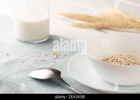 Un petit déjeuner sain, un mélange de flocons de céréales, de muesli dans un bol blanc et de lait dans une bouteille Banque D'Images