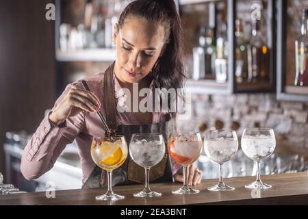 Le barmaid prépare une sélection de cinq boissons toniques de gin différentes au bar. Banque D'Images