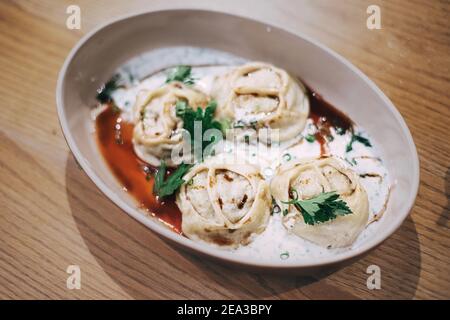 Manti - un plat de délicatesse de l'Asie centrale, est un parent de boulettes et raviolis. Servi avec de la sauce sur une assiette dans un café Banque D'Images