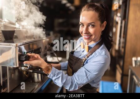 Un barista professionnel et bien habillé vole sa machine à café dans un café. Banque D'Images