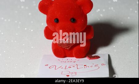 Ours en peluche rouge avec coeur brillant avec enveloppe de Saint-Valentin comme cadeau ou cadeau le jour de la Saint-Valentin sur fond blanc brillant. Banque D'Images