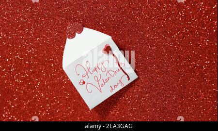 Concept de salutation de la Saint-Valentin, enveloppe ouverte avec coeurs rouges sur fond rouge brillant. Banque D'Images