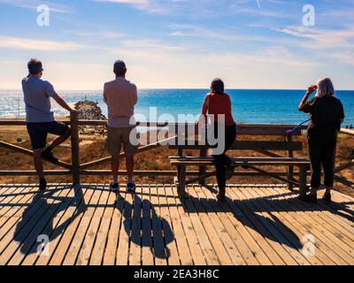 Marbella, Malaga, Espagne. Octobre 2020. Quatre touristes avec leur dos ont tourné regardant la mer sur une plate-forme d'observation en bois sur la côte de Marbella Banque D'Images