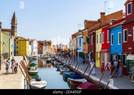 Burano, Italie, 2020 septembre – les touristes se baladent le long d'un canal typique de Burano avec des maisons colorées et une boutique de cadeaux Banque D'Images