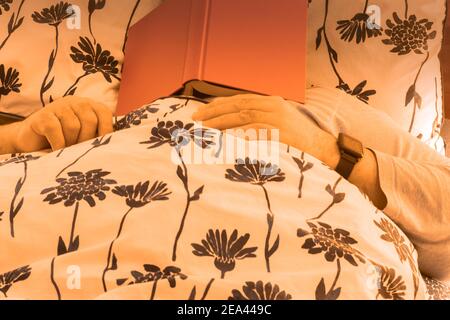 attention sélective avec un homme détendu avec un livre sur son visage allongé sur le lit à la maison fatigué et endormi Banque D'Images