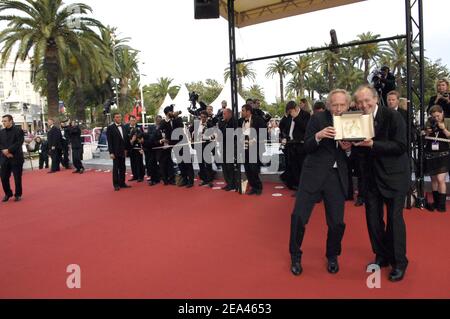 Les réalisateurs belges, les frères Luc Dardenne (R) et Jean-Pierre Dardenne montrent le trophée Palme d'Or qu'ils ont remporté samedi pour leur film 'l'enfant', alors qu'ils arrivent sur le tapis rouge pour la cérémonie de clôture du 58e Festival international du film de Cannes, dans le sud de la France, le 22 mai 2005. Photo de Hahn-Nebinger-Klein/ABACA Banque D'Images