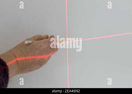 Un spécialiste marque un point sur un mur avec un laser électronique Banque D'Images