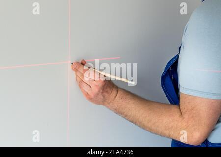 Un spécialiste marque un point sur un mur avec un laser électronique Banque D'Images