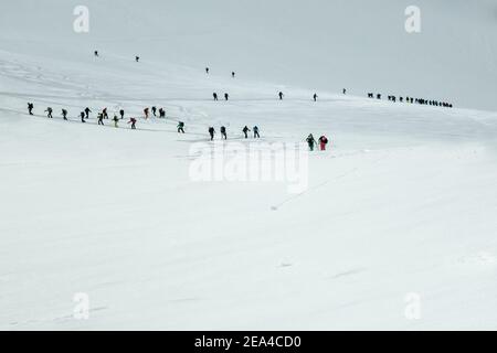 Longue file de skieurs de randonnée dans la partie fermée De la station de ski de Grand Montets en direction de Le haut de commencer leur haute route vers Zerma Banque D'Images