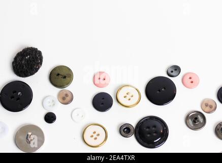 Boutons en plastique multicolore pour les vêtements à plat sur fond blanc. Vue de dessus de la table. Accessoires pour la couture et la réparation de vêtements. Condition élevée Banque D'Images