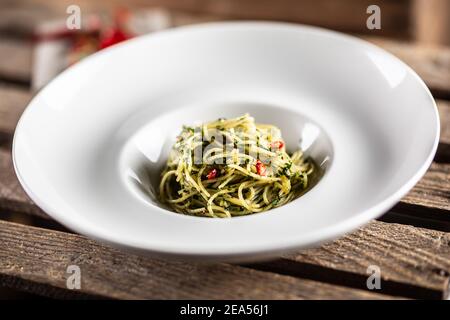 Spaghetti aglio e olio à l'huile d'olive, gralique, basilic, tomates et piments servis sur un plat profond. Banque D'Images