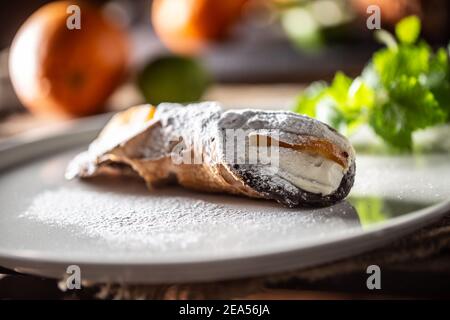 Dessert sucré de Cannoli sicilien recouvert de sucre servi sur une assiette. Banque D'Images