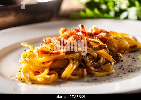 Plaquée de spaghetti carbonara italien avec jambon sur le dessus. Banque D'Images