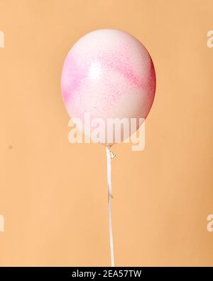 Grand ballon gonflable en latex blanc à l'hélium avec peinture en aérosol rose décorations sur anniversaire mariage corporatif fête sur beige Banque D'Images