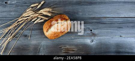 Vue de dessus de pain complet de levain maison avec tiges de blé séchées sur des planches de bois altérées Banque D'Images