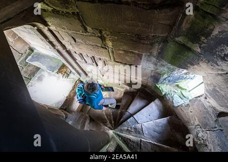 Touriste regardant les vieux graffiti dans l'escalier en colimaçon, Ashby de la Zouch Castle, Leicestershire, Angleterre, Royaume-Uni Banque D'Images