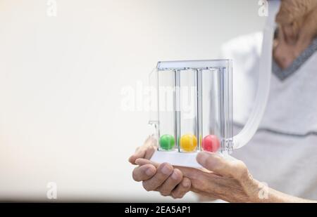 L'ancienne main du patient tenant la spirométrie incitative à trois balles est un équipement médical pour la post-opération. L'équipement pour le test de fonctionnement des poumons et Pul Banque D'Images