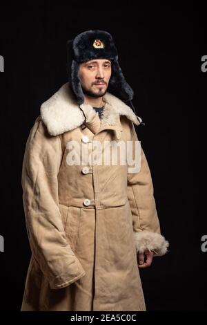 Portrait d'un homme d'apparence caucasienne dans un soviétique chapeau de fourrure d'officier et manteau de peau de mouton de l'armée Banque D'Images