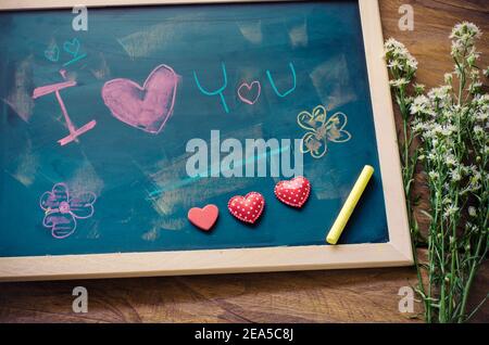 Tableau noir avec des mots écrits en choc que le "je T'AIME" et un coeur floral a été placé à côté du tableau - le concept de la Saint-Valentin. Banque D'Images