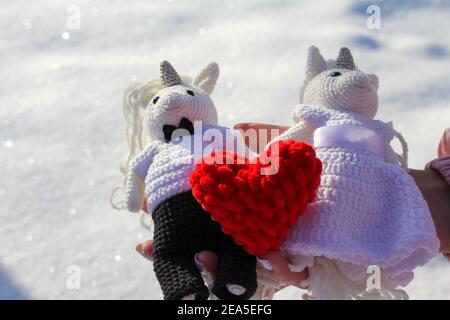 Histoire d'amour pour la Saint-Valentin, cœur rouge entre les mains comme symbole de l'amour sur fond de neige Banque D'Images