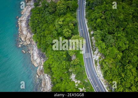 Vue aérienne de la route entre le cocotier et le grand océan en journée à Nakhon si Thammarat, Thaïlande Banque D'Images