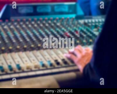 Console de mixage d'ingénieur en son flou en salle de concert. Ingénieur du son flou main utilisant le curseur de mixage audio travaillant dans la scène montre les performances. Banque D'Images