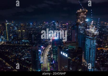 Vue aérienne nocturne des gratte-ciel en construction et du centre-ville moderne avec autoroute à plusieurs voies à Jakarta, Indonésie Banque D'Images