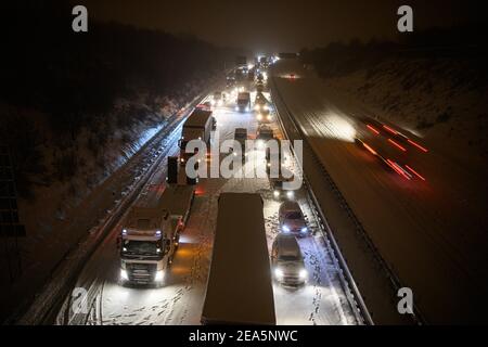 Dresde, Allemagne. 08 février 2021. Les voitures et les camions sont coincés dans un embouteillage au début de la matinée, lors de la chute de neige sur l'Autobahn 4 neigeux, près de Dresde, tandis qu'un homme se tient à côté de sa voiture. Credit: Robert Michael/dpa-Zentralbild/dpa/Alay Live News Banque D'Images