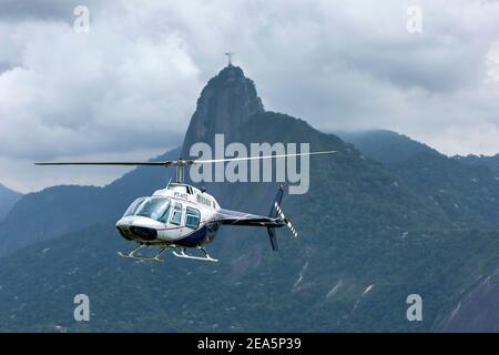 Un hélicoptère survole Rio de Janeiro au Brésil. En arrière-plan se trouve la statue du Christ Rédempteur sur la montagne du Corcovado. Banque D'Images
