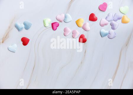 Petites formes de coeur colorées sur fond de marbre blanc. Minuscules coeurs d'or scintillant . Saint Valentin. Sur l'amour. Photo de haute qualité Banque D'Images