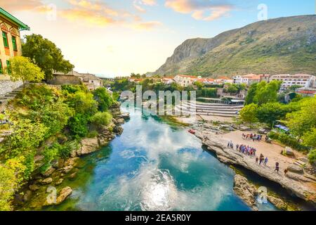 Vue sur la rivière Neretva et les touristes depuis le sommet du Stari Most, le vieux pont dans le village médiéval des Balkans de Mostar, Bosnie-Herzégovine Banque D'Images