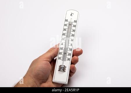 Thermomètre en bois avec échelle Celsius dans la main d'un homme sur fond blanc. Banque D'Images