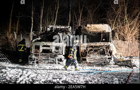 Hambourg, Allemagne. 08 février 2021. Un pompier passe devant l'épave de deux camions brûlés sur un site de la société dans le quartier de Wilhelmsburg à Hambourg. Selon les premiers résultats, on soupçonne un incendie criminel. Credit: Daniel Reinhardt/dpa/Alay Live News Banque D'Images