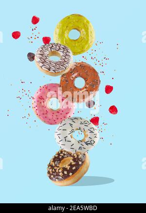 Lévitation alimentaire - beignets doux et colorés volant dans l'air avec des framboises et des saupoudriers colorés. Banque D'Images