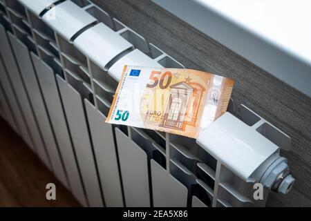 Le concept de payer pour le chauffage dans les maisons avec un climat froid. L'argent comptant est couché sur un radiateur en métal blanc près de la fenêtre. Banque D'Images