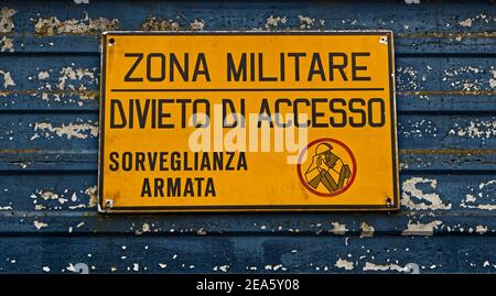 Zone militaire italienne avec panneau jaune: 'Military zone, no Entry, armé surveillance'. 'Zona militare, divieto di accesso, sorveglianza armata' Banque D'Images