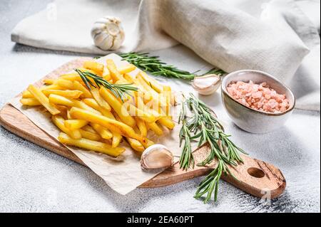 Frites sur planche à découper, pommes de terre frites. Arrière-plan blanc. Vue de dessus Banque D'Images