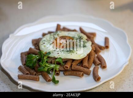 Œuf frit avec nouilles de sarrasin et arugula sur plaque blanche Banque D'Images