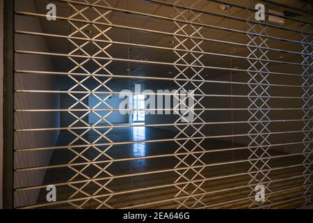 Grille de protection fermée à volet roulant en métal devant un magasin vide dans un centre commercial, crise économique et insolvabilité en raison d'un lockdow de détail Banque D'Images